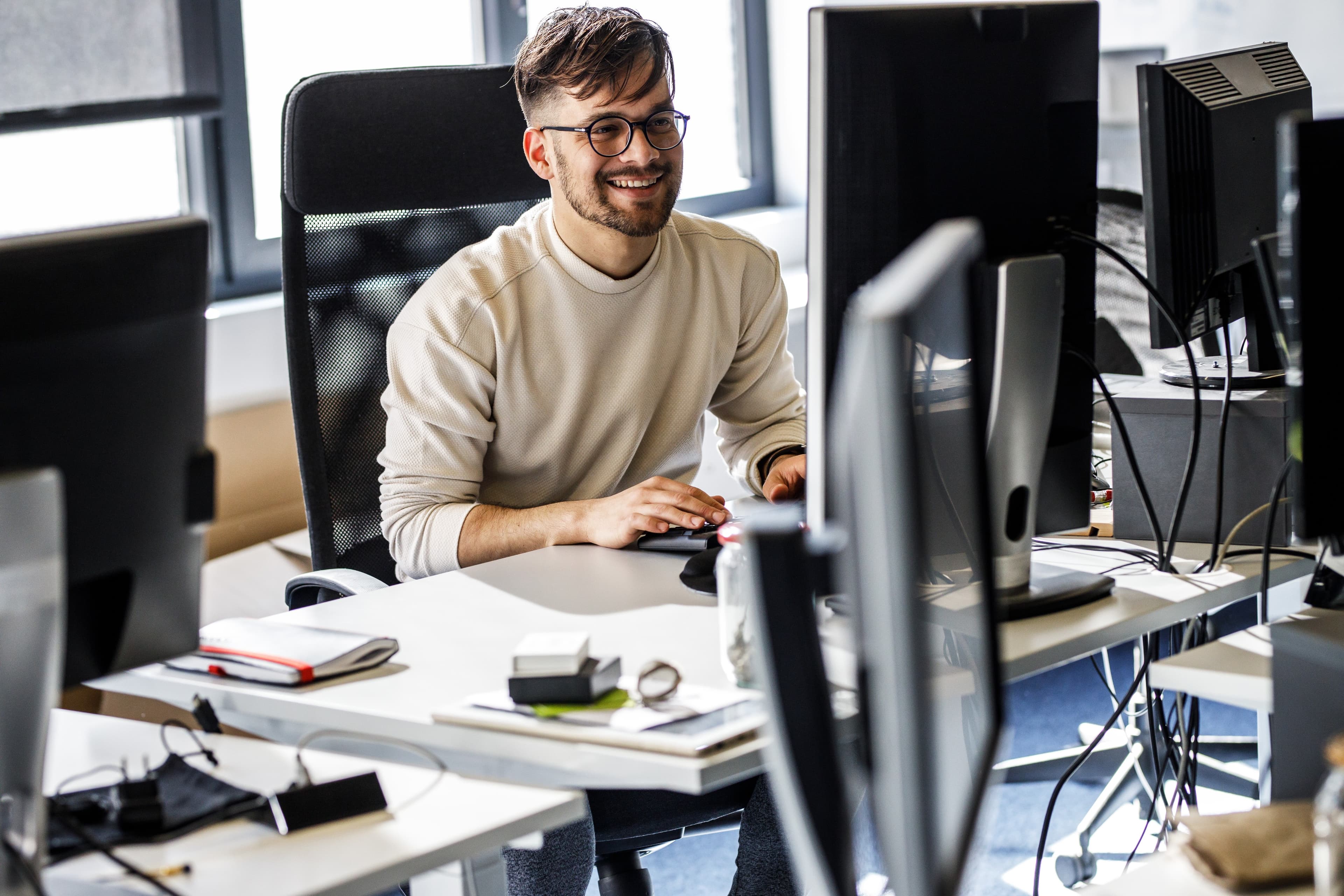 Software engineer at a multi-monitor workstation, representing pre-IPO tech employees evaluating QSBS Section 1202 stock option tax planning.
